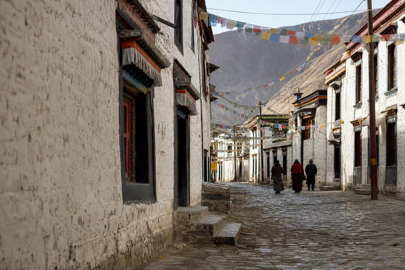 An old-town lane strung with prayer flags
